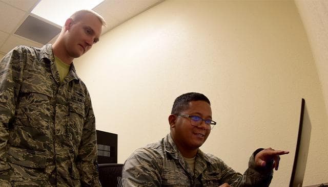 Two U.S. Air Force personnel use a computer to conduct a virtual exercise to train for cyber attacks.