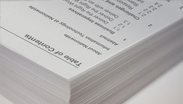 Table of contents for a technical report in black ink sits atop a stack of white papers.
