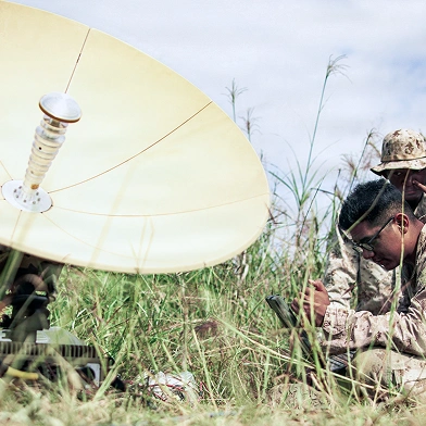 Military personnel setting up equipment a field.