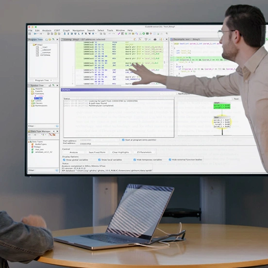 Two colleagues reviewing code on a large screen.