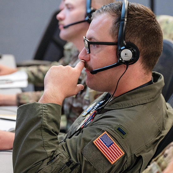 US Airmen wearing headsets while working at computers.