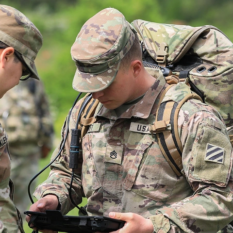 US Army soldiers reviewing information on a handheld device.