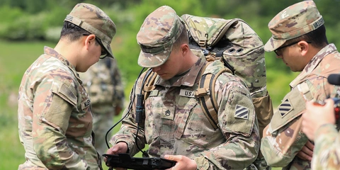 US Army soldiers reviewing information on a handheld device.