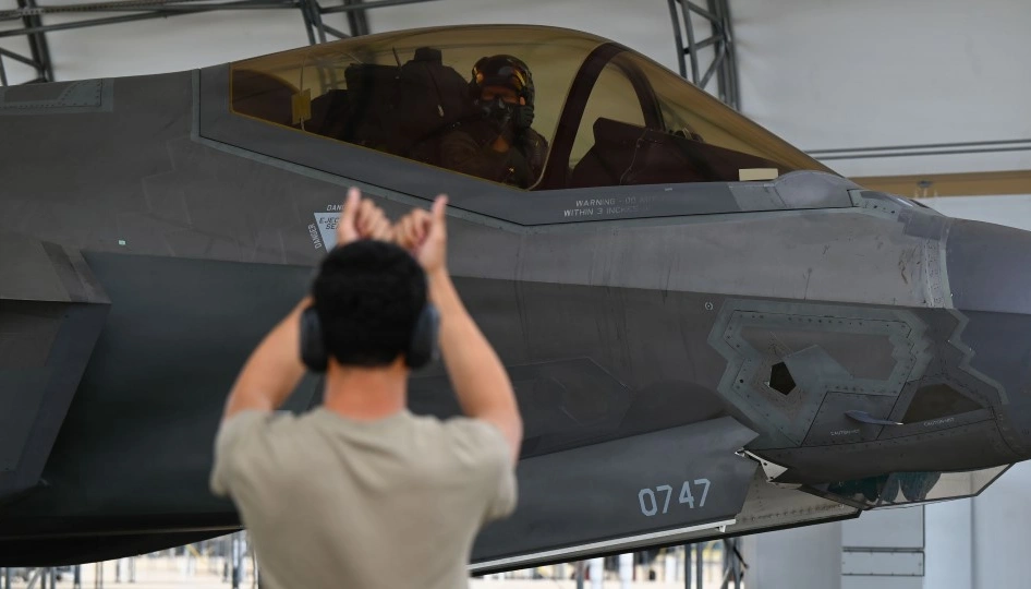 Ground crew signals to the pilot of an F-35A.