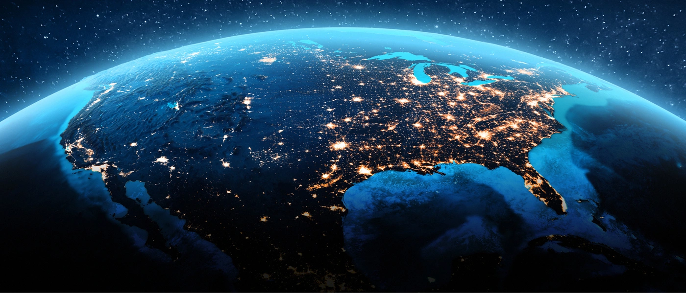 View of Earth from space at night, showing the United States illuminated by city lights.