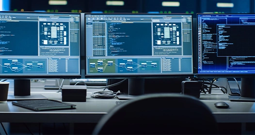 Three computer monitors on a desk displaying various code.