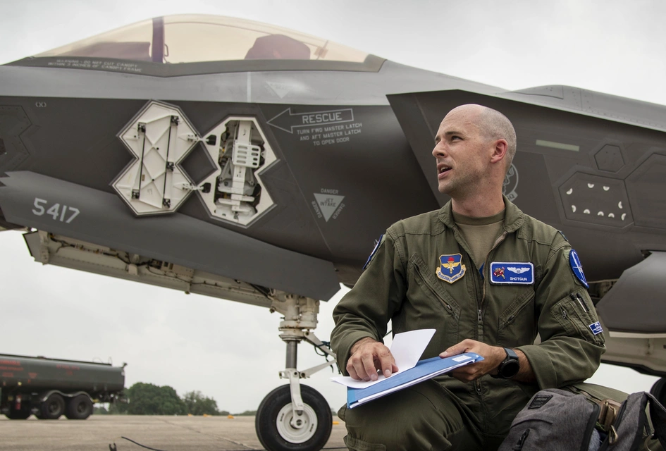Pilot reviewing paperwork next to a F-35 jet.