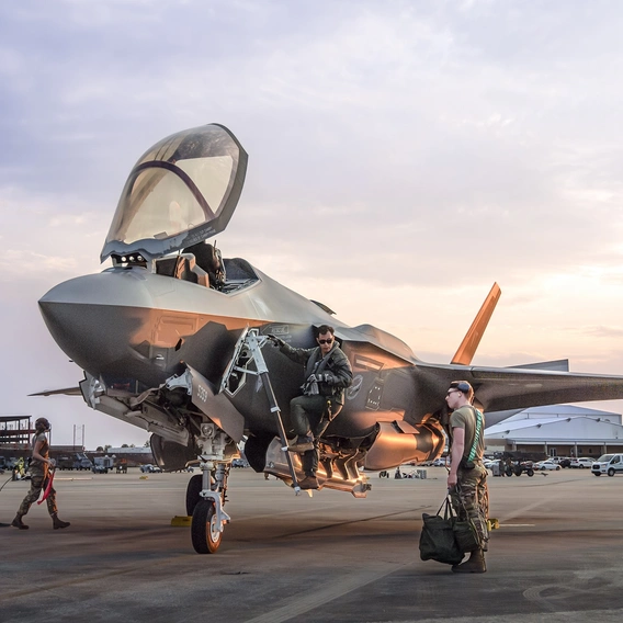 A pilot entering the cockpit of an F-35 fighter jet.