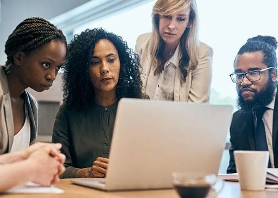 A group of professionals looking at a laptop screen.