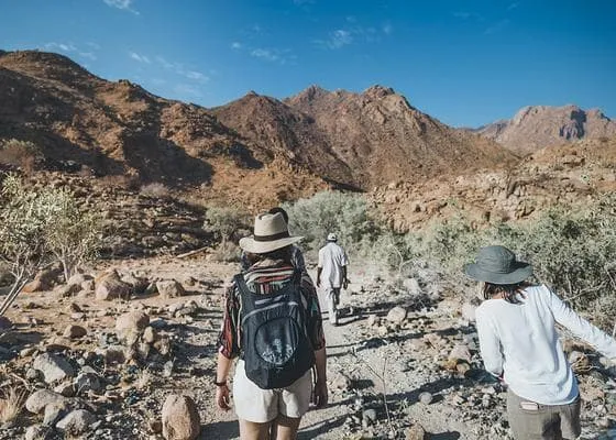 Characterizing and Detecting Mismatch in ML-Enabled Systems Challenge Image - Two people in hiking gear, crossing an arid wilderness, approaching a small mountain.