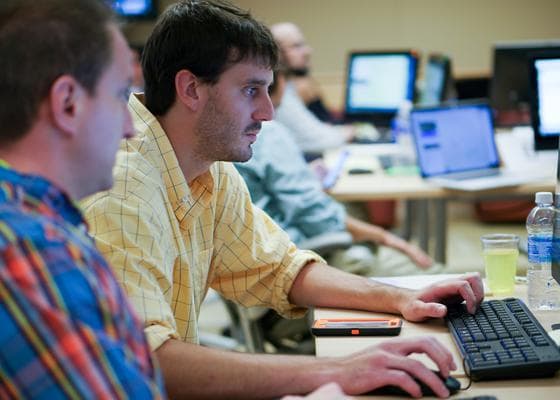 Individuals at computers participating in the Crisis Simulation Case Solution.