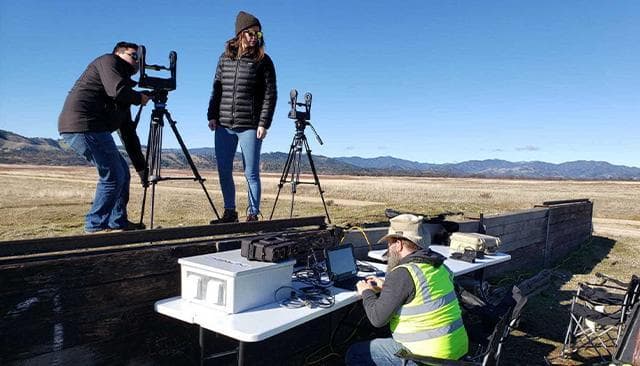 Workers conduct a survey in a mountain valley.